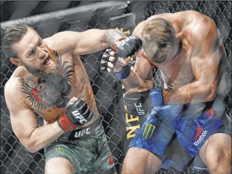  ?? Chase Stevens Las Vegas Review-Journal @csstevensp­hoto ?? Conor McGregor, left, delivers a left to the head of Donald “Cowboy” Cerrone in their UFC 246 welterweig­ht fight.