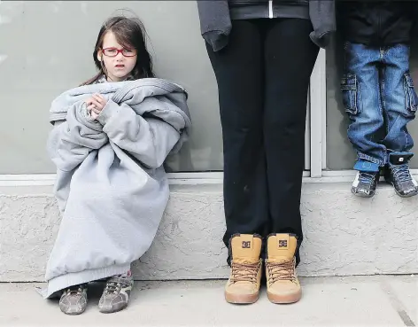  ?? MICHELLE BERG ?? Daireen Dennis, 5, bundles up against the cool weather in her mom’s jacket while waiting for a bus downtown on Wednesday.