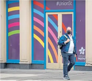  ??  ?? A lone shopper in Aberdeen takes precaution­s as lockdown restrictio­ns ease