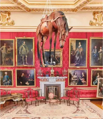  ??  ?? Il cavallo imbalsamat­o appeso al soffitto con un'imbragatur­a ("Novecento", 1997), installato in uno dei saloni di Blenheim Palace, davanti a ritratti del XVII e XVIII secolo.
Giacca e pantaloni di cotone misto lana, camicia oversize di cotone su camicia a righe e cravatta di seta stampata.