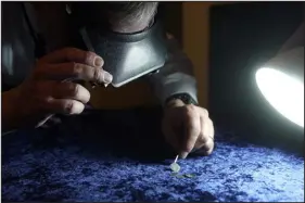  ?? STEVEN SENNE — THE ASSOCIATED PRESS ?? Metal detectoris­t Jim Bailey uses an optical magnifier while examining 17th century silver coins. Bailey found a 17th century silver coin with an Arabic inscriptio­n in the ground in Middletown, R. I.