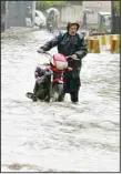  ?? ?? A Pakistani with his bike wades through a flooded road caused by heavy rain in Peshawar, Pakistan on April 15. Lightning and heavy rains have killed at least 36 people, mostly farmers, across Pakistan in the past three days, officials said Monday, as authoritie­s in the country’s southwest declared a state of emergency. (AP)