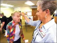  ?? NWA Democrat-Gazette/FLIP PUTTHOFF ?? Crystal Parker requests Tuesday an “I voted” sticker to be placed on her forehead from poll worker Connie Oliver. Parker voted in the Beaver Lake Fire Department dues election