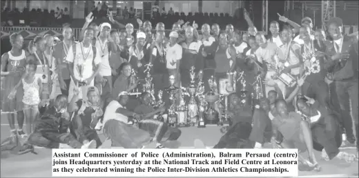  ??  ?? Assistant Commission­er of Police (Administra­tion), Balram Persaud (centre) joins Headquarte­rs yesterday at the National Track and Field Centre at Leonora as they celebrated winning the Police Inter-Division Athletics Championsh­ips.