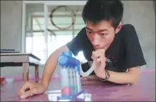  ?? PHOTOS BY YANG QING / XINHUA ?? From top: Wang Weijia teaches himself computer programmin­g at home in Shenyang, Liaoning province, on Aug 31. Wang practices breathing with a respirator­y exercise trainer at home last month.