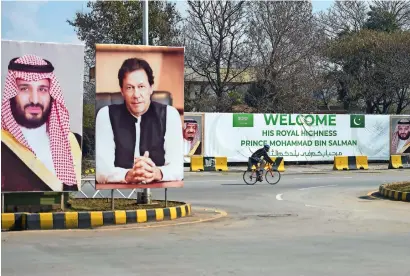  ?? AFP ?? A cyclist rides past billboards showing portraits of Saudi Arabia’s crown Prince Mohammed bin Salman and Pakistan’s Prime Minister Imran Khan and a banner welcoming the prince ahead of his arrival in Islamabad on Friday. —