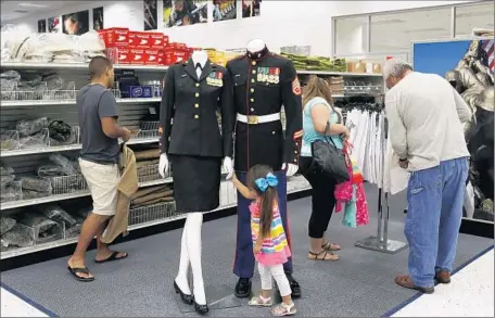  ?? Photog raphs by Katie Falkenberg Los Angeles Times ?? MAKAYLA BALDERAS admires the uniforms for sale as she shops on base with her family. “We build communitie­s,” says family housing director Robert Marshall, “just like the housing outside the fence.” That includes three “big box” stores and 20 fast-food...