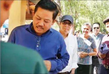 ?? PHA LINA ?? RFA Khmer Service deputy director Chun Chanboth (middle, with cap) stands in a queue between CNRP lawmakers Long Ry (left) and Mu Sochua at Phnom Penh’s Prey Sar prison on Wednesday.