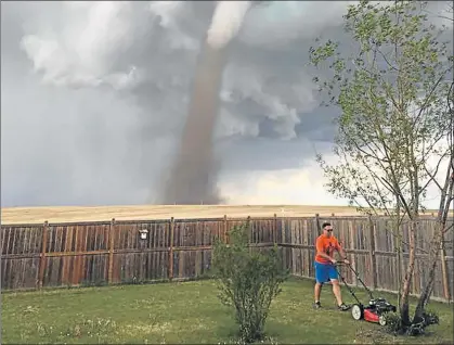  ?? Picture: SUPPLIED ?? ORDINARY LIFE: The photograph that South African Theunis Wessels’s wife took of him mowing their lawn at their home in Canada, as a massive tornado looms in the background