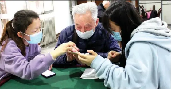  ?? JI YUAN / CHINA DAILY ?? Young volunteers in Xi’an, Shaanxi province, help a senior use his phone.