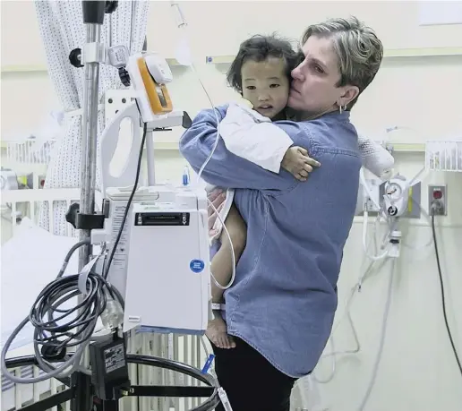  ?? The Canadian Press ?? Johanne Wagner holds her three-year-old daughter, Phuoc, before the girl’s liver transplant in Toronto on Tuesday.