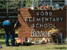  ?? JAE C. HONG/AP ?? A law enforcemen­t worker lights a candle Wednesday at Robb Elementary School in Uvalde, Texas, where at least 21 people were killed Tuesday.