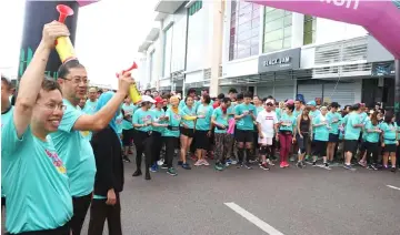  ??  ?? Dr Sim (left), accompanie­d by Roslan, flagging-off the KPJ Kuching Colour Run 2018 For Cancer Awareness at Saradise, BDC.
