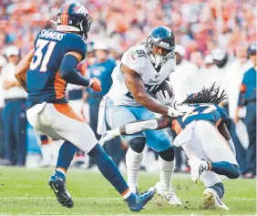  ?? AAron Ontiveroz, The Denver Post ?? Broncos safety Justin Simmons, left, joins cornerback Davontae Harris in stopping the Titans’ Jonnu Smith during the fourth quarter.