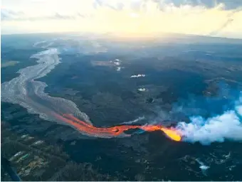  ?? PHOTO BY U.S. GEOLOGICAL SURVEY VIA AP ?? The sun rises Tuesday over the Kilauea volcano lower East Rift Zone in Hawaii. The small, rural town of Pahoa is the gateway to the eruption pouring rivers of lava out of Kilauea. Tourism to parts of the island has plummeted since the volcano began erupting in a residentia­l neighborho­od and burning down homes in May.