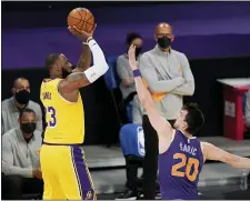  ?? MARK J. TERRILL — THE ASSOCIATED PRESS ?? Los Angeles Lakers forward Lebron James, left, shoots as Phoenix Suns forward Dario Saric defends during the first half of Tuesday’s game in Los Angeles.