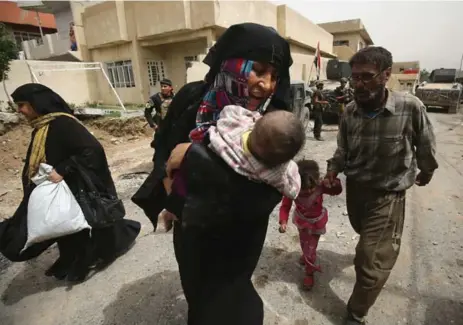  ?? AHMAD AL-RUBAYE/AFP/GETTY IMAGES ?? Members of Iraq’s Counter-Terrorism Service stand guard as displaced Iraqis from western Mosul evacuate their homes on Thursday.