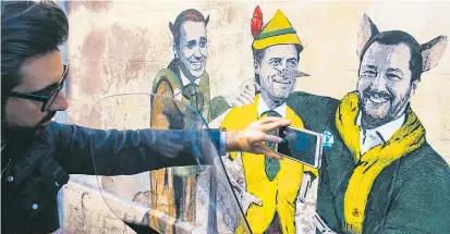  ??  ?? Ein Graffito in Rom zeigt Di Maio als Katze und Salvini als Fuchs, die Pinocchio Conte manipulier­en.