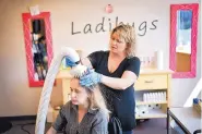  ?? GLEN STUBBE/MINNEAPOLI­S STAR TRIBUNE ?? Ladibugs manager Christina Doran treats a client with an AirAlle device, which uses air hot enough to kill lice but not burn the patient.