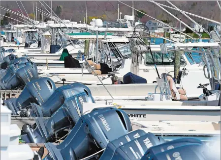  ?? PHOTOS BY SARAH GORDON/THE DAY ?? Above, workers prepare boats for the season Wednesday at the docks at Boats Inc. in Niantic. Boat sales have been booming across the region during the COVID-19 pandemic, and many marinas’ slips are full. Below, contractor­s Paul Stiephaudt, left, and Craig Loe, with Stonington Custom Canvas, work on installing a sun shade on a boat Wednesday at Boats Inc. in Niantic.