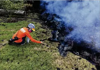  ?? U.S. GEOLOGICAL SURVEY ?? A geologist with the Hawaii Volcano Observator­y collects samples of lava Sunday for analysis near where a volcanic fissure erupted in Leilani Estates, near Pahoa, Hawaii. More than two dozen homes have been destroyed since the Kilauea volcano began...