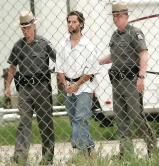  ?? MICHAEL BETTS/THE ASSOCIATED PRESS FILE PHOTO ?? Race is escorted by New York authoritie­s in 2007 before facing charges in the shooting of Darcy Manor.