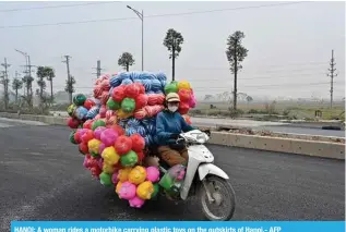  ?? ?? HANOI: A woman rides a motorbike carrying plastic toys on the outskirts of Hanoi.- AFP