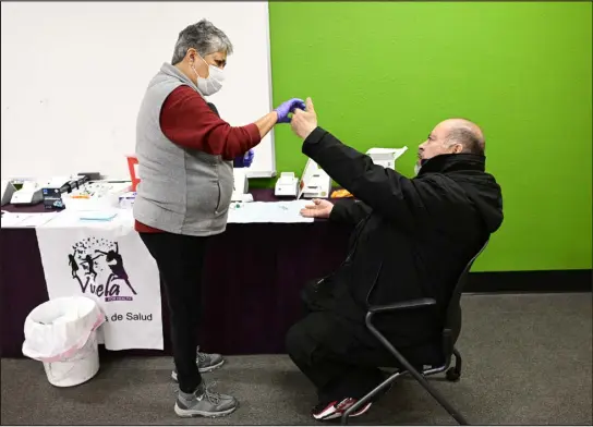  ?? ANDY CROSS — THE DENVER POST ?? Vuela for Health community health worker Diane Medina, left, works with patient Mario Marquez during a heart health screening event at Vuela for Health in Denver on Feb. 25.