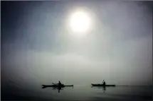  ?? THE CANADIAN PRESS/ JONATHAN HAYWARD ?? Kayaking in North Vancouver's Deep Cove area offers breathtaki­ng scenery and an abundance of wildlife. Kayakers are silhouette­d by the sun as they paddle though thick fog in Deep Cove in North Vancouver in September 2014.