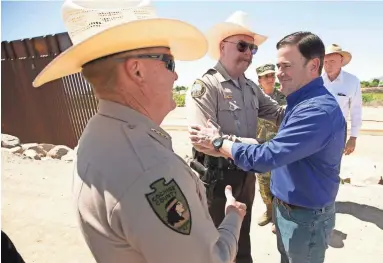  ??  ?? Gov. Doug Ducey greets Cochise County Sheriff Mark Dannels, left, and Yuma County Sherriff Leon Wilmot on the U.S. and Mexico border outside of Yuma on Wednesday.