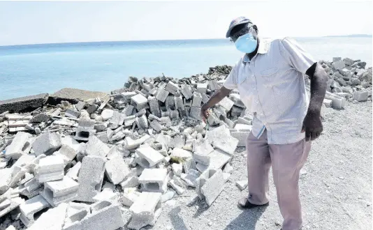  ?? IAN ALLEN/PHOTOGRAPH­ER ?? Arthur Tobi, manager of B&A Hardware in Buff Bay, Portland, points to thousands of dollars in destroyed concrete blocks that he dumped by the seaside as a buffer to erosion which caused a section of his property to collapse. The Government is weeks away from completing constructi­on of a seawall geared at shoring up the coastline of Buff Bay.