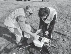  ?? PROVIDED TO CHINA DAILY ?? Technician­s in Australia load a drone with grass seeds for post-fire recovery work.