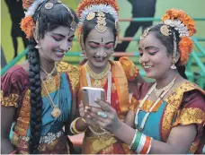  ??  ?? Indian girls examine a mobile phone before Independen­ce Day celebratio­ns in Secunderab­ad, Hyderabad’s twin city