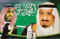  ?? Associated Press file photo ?? People walk past a banner showing Saudi King Salman, right, and his Crown Prince Mohammed bin Salman, outside a mall in Jiddah, Saudi Arabia in 2020.