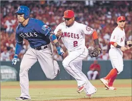  ?? Jonathan Moore Getty Images ?? ANGELS SHORTSTOP Erick Aybar runs down Robinson Chirinos, but not before Chirinos’ RBI single gave the Rangers a 3-1 lead in the fifth inning.