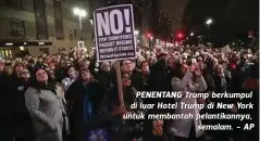  ??  ?? PENENTANG Trump berkumpul di luar Hotel Trump di New York untuk membantah pelantikan­nya,
semalam. - AP