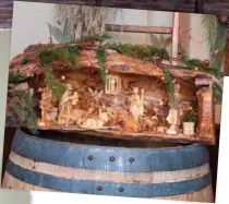  ??  ?? An olive-wood Nativity scene, topped with sprigs of green, hews to its humble roots when displayed atop a weathered barrel.