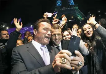  ?? Thibault Camus/Associated Press ?? French President Emmanuel Macron, center, and Arnold Schwarzene­gger take a selfie in front of the Eiffel Tower after the One Planet Summit on Tuesday in Paris.