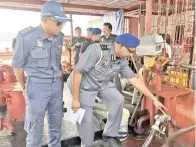  ??  ?? RAVICHANDR­AN dan Usman meneliti pam minyak yang tidak diluluskan pihak inspektor timbang dan sukat.