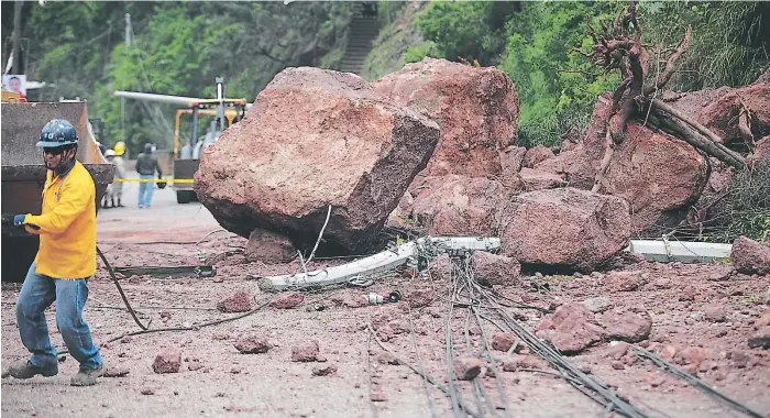  ??  ?? Parte de las gigantesca rocas que cayeron sobre la vía producto del derrumbe en la colonia Villa Nueva. Unas ocho horas se trabajó para abrir el paso a los vehículos en la zona.