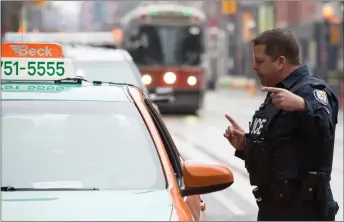  ?? CP PHOTO ?? A police constable speaks to a taxis driver during the second day of the King Street Transit Pilot involving city streetcars on Monday.