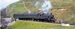  ?? R. PATTERSON/COLOUR RAIL ?? Ivatt ‘2MT’ No. 41312 drifts into Corfe Castle on May 9 1964 with a Swanage-bound train comprised of a Maunsell two-coach pull-push set.