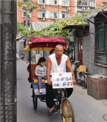  ??  ?? On September 25, 2017, an old man takes tourists sightseein­g in Beijing's hutongs. IC