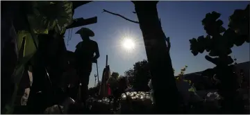  ?? AP PHOTO ?? Roberto Marquez adds a cross to a makeshift memorial at the site where officials more than 50 people dead in an abandoned semitraile­r containing suspected migrants, Thursday, in San Antonio.