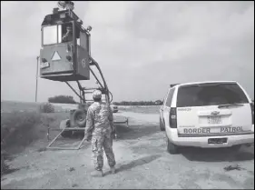  ?? AP PHOTO ?? A member of the U.S. National Guard checks on his colleague inside a Border Patrol Skybox near the Hidalgo Internatio­nal Bridge in Hidalgo, Texas.