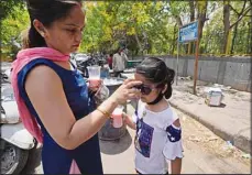  ?? ?? A woman puts on a sunglass for her child on a hot day in New Delhi, May 14. The temperatur­e in New Delhi reached 45 Degrees Celsius. (AP)