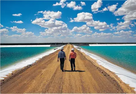  ?? Michael Ciaglo photos / Houston Chronicle ?? Layne Christense­n’s Byron Bevers, left, and Tim Patrick walk between water retention ponds for the new project in Pecos.