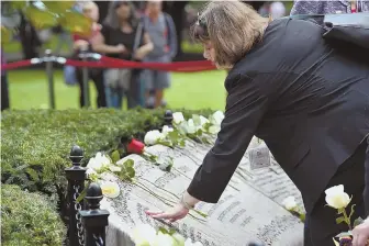  ?? STAFF PHOTOS BY FAITH NINIVAGGI ?? REMEMBERIN­G: Dorothy Grodberg and Diane Hunt, top, embrace during the 17th annual Massachuse­tts Commemorat­ive Ceremonies on the anniversar­y of the Sept. 11 attacks, in Boston. Leslie Blair, above, touches her sister Susan Blair’s name on the memorial and Bernadette DiNunzio, right, pauses for a moment in the garden.