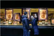  ?? KIRSTY WIGGLESWOR­TH / AP ?? A woman takes a photo in front of a shop in London on Tuesday. In his new book, Prince Harry lambastes the U.K. press and the royal family.