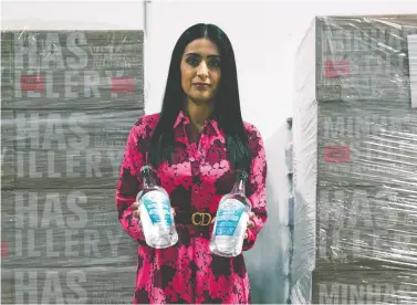  ?? SUPPLIED ?? Manjit Minhas, co-founder and chief executive officer of Minhas Breweries and Distillery, with some of the hand sanitizer they
have produced. The company has donated more than 100,000 bottles of the cleaner.